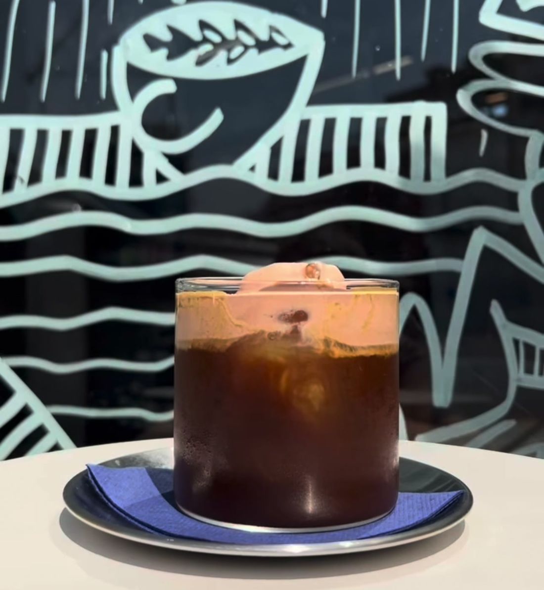 Cloud Chocolate Espresso sobre plato azul con fondo ilustrado