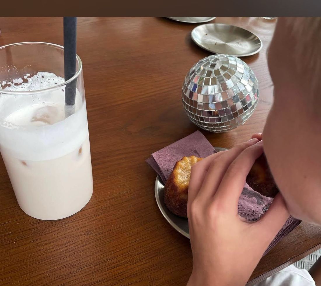 Vaso de cold brew con hielo junto a una mano en la mesa