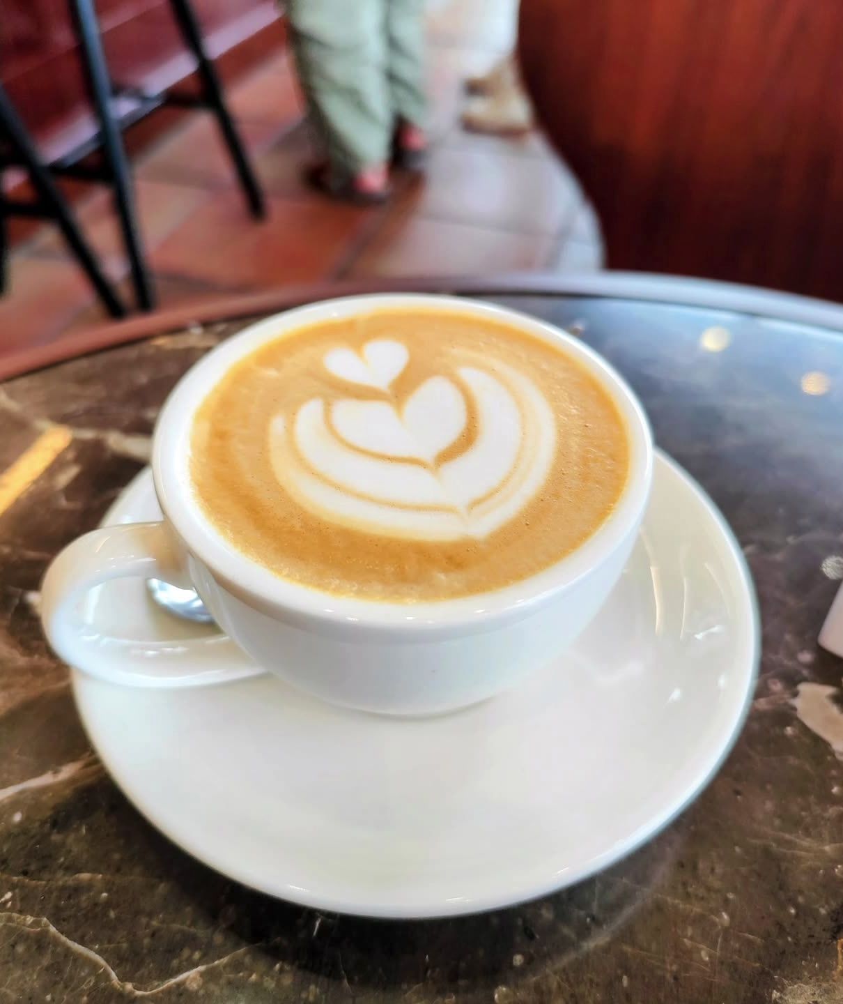 Cappuccino con corazón de latte art en mesa metálica