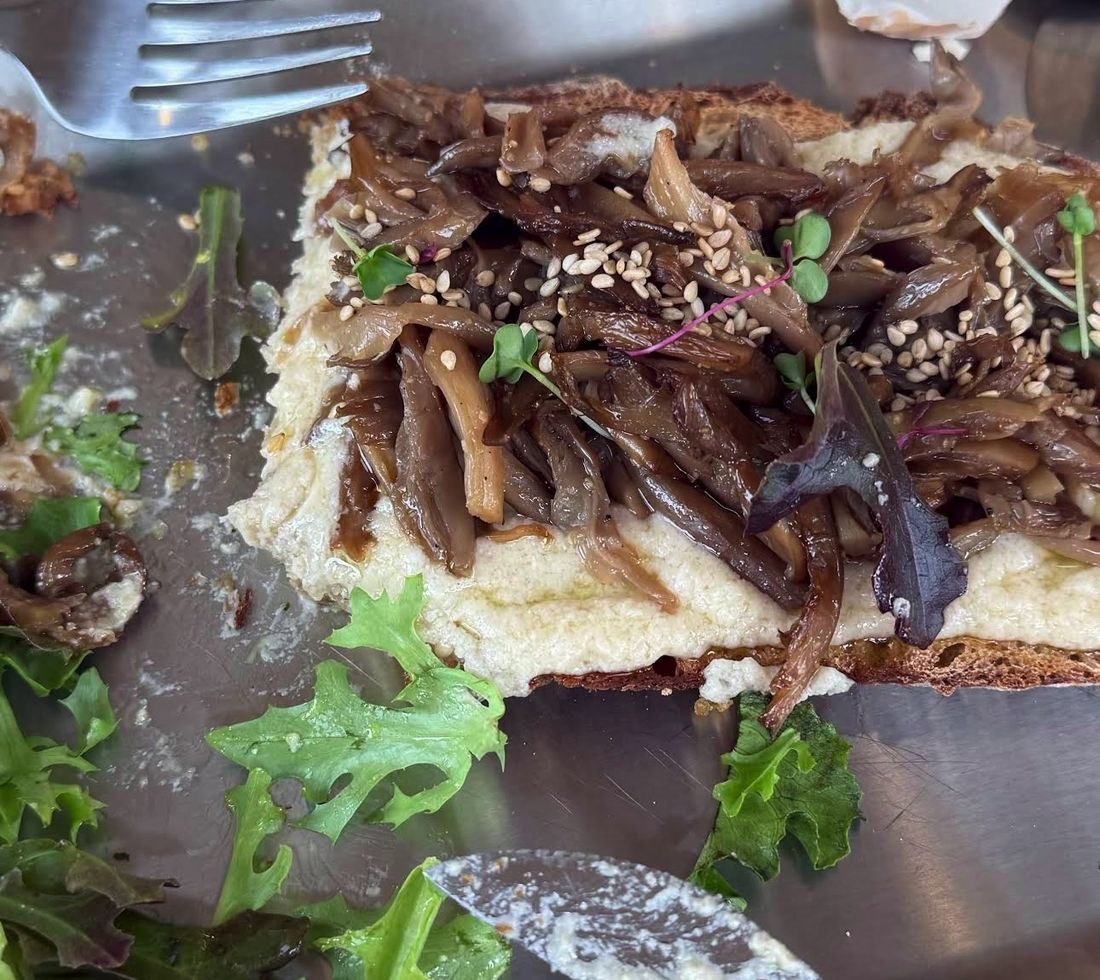 Tostada de setas con huevo cocido y brotes sobre bandeja de metal